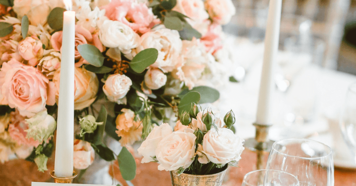 Table with lit candles and wedding flowers for natural glam bridal makeup inspiration.